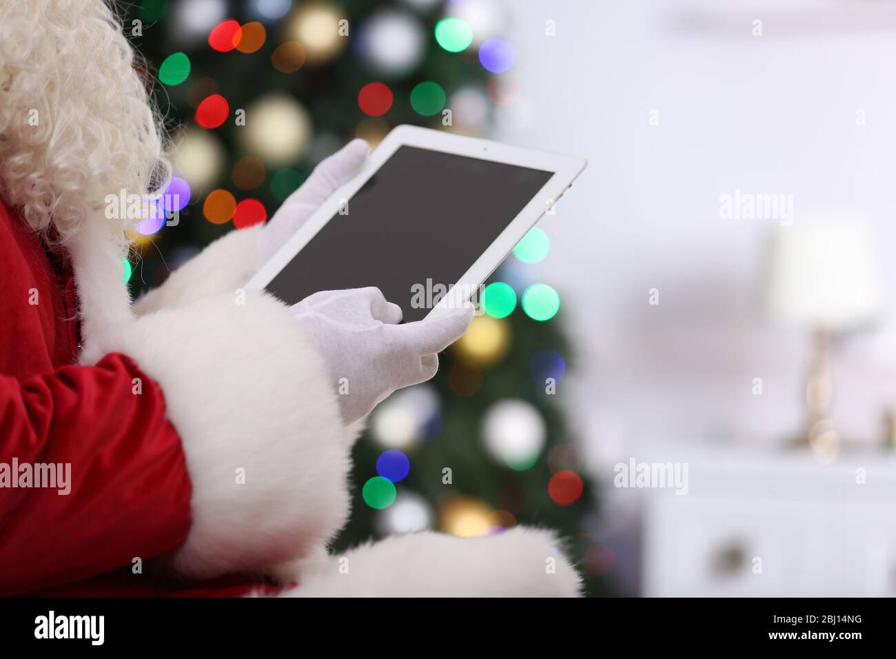 Père Noël tenant une tablette sur fond d'arbre de Noël Banque D'Images