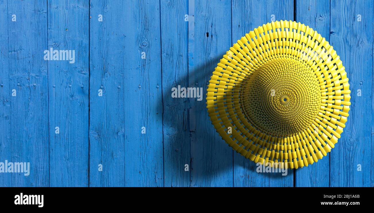 Chapeau de paille jaune d'été sur fond de mur bleu en bois. Accessoire pour tête de plage pour la protection solaire, espace de copie. illustration tridimensionnelle Banque D'Images