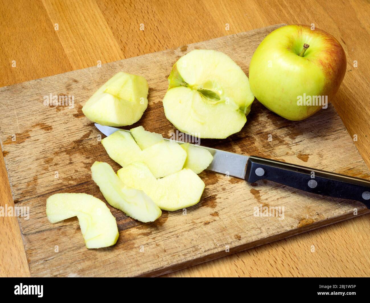 Hacher des pommes sur une planche à découper en bois sur une table de cuisine Banque D'Images