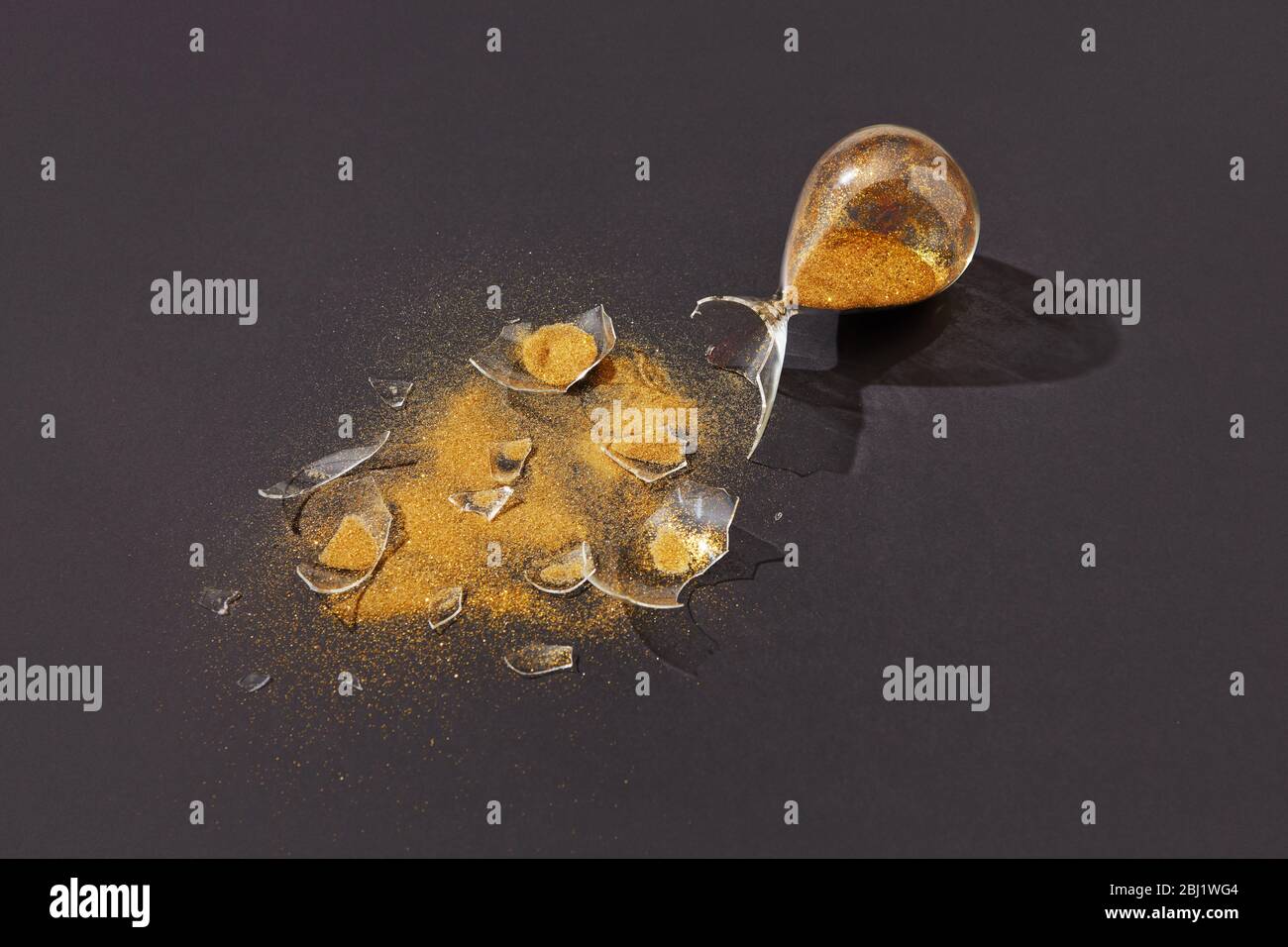 Sablier écrasé avec du sable doré sur un fond noir. Banque D'Images