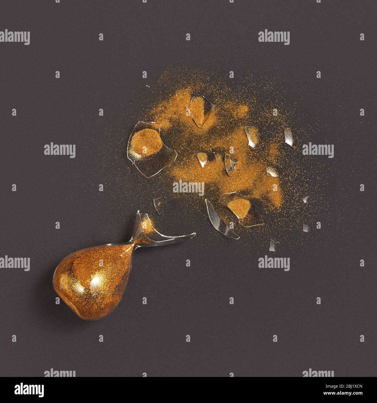 Sablier cassé de vieillesse avec sable doré sur fond noir. Banque D'Images