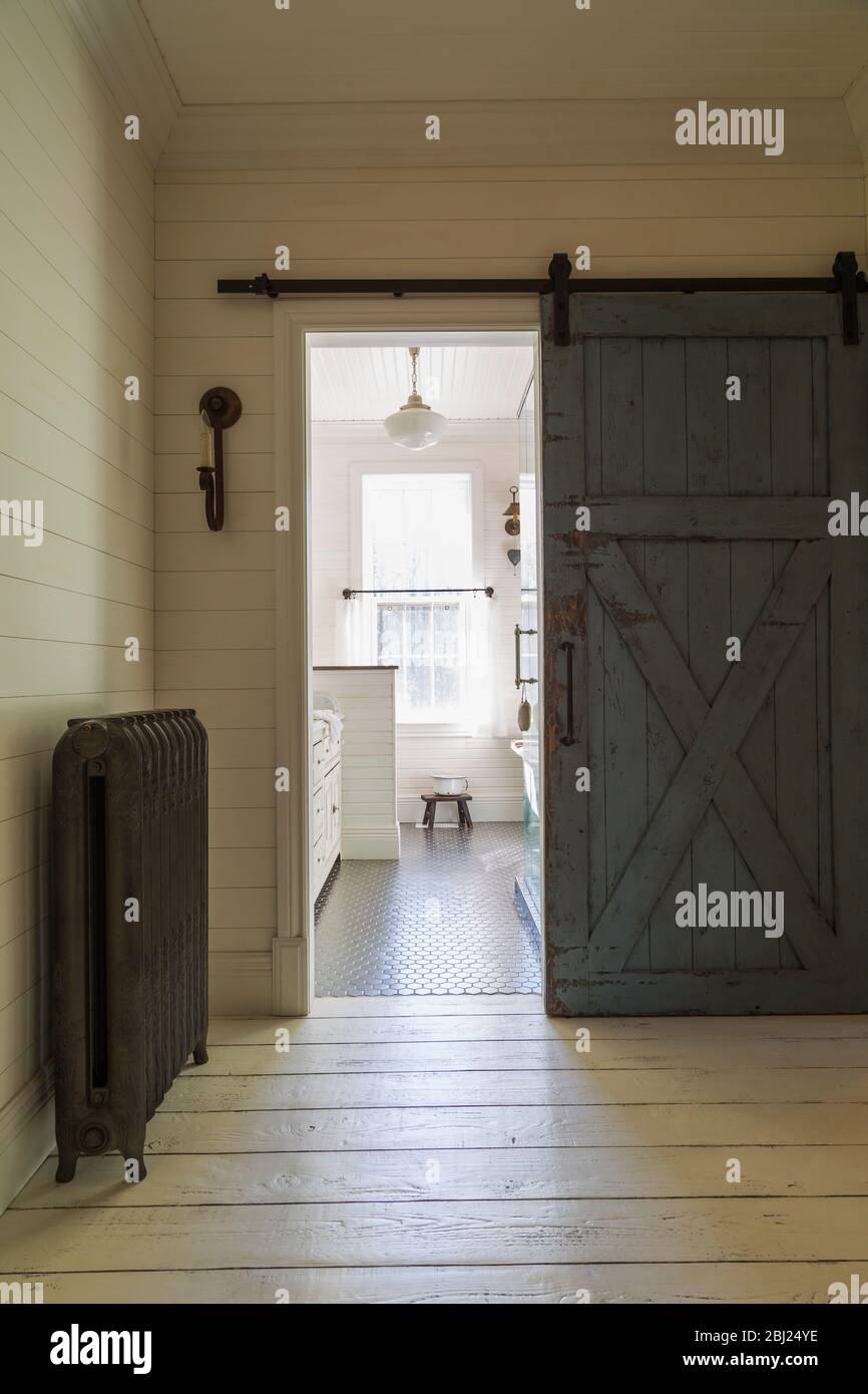 Vue par une porte coulissante sur une salle de bains avec sol carrelé noir,  murs lambrissés crème et fenêtres à guillotine Photo Stock - Alamy