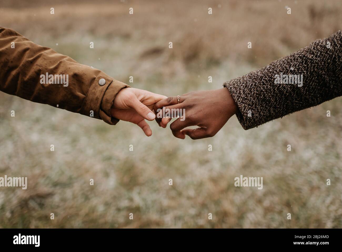 Couple interracial, homme et femme tenant les mains, un portant un anneau de mariage d'or. Banque D'Images