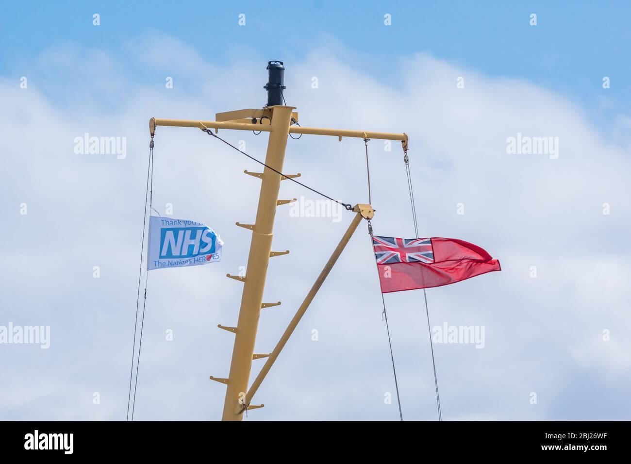 NHS, le drapeau des héros de remerciement, avec panneau rouge endévolant sur mât sur le seigneur de ferry Calmac des îles dans les Hébrides extérieures de l'Uist du Sud, Ecosse Banque D'Images