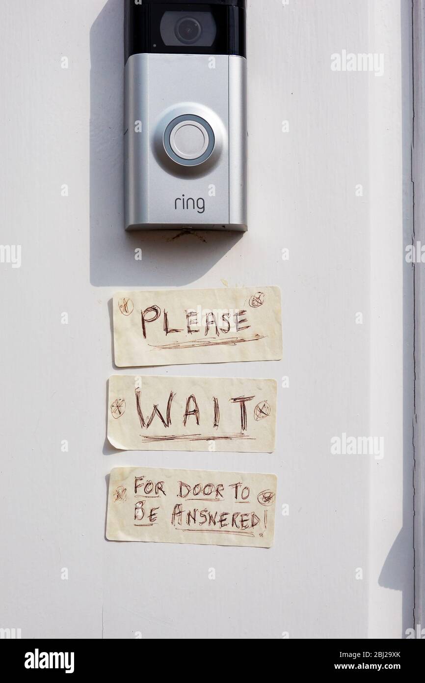 Bouton de cloche de porte avec message écrit à la main sur des autocollants blancs Banque D'Images