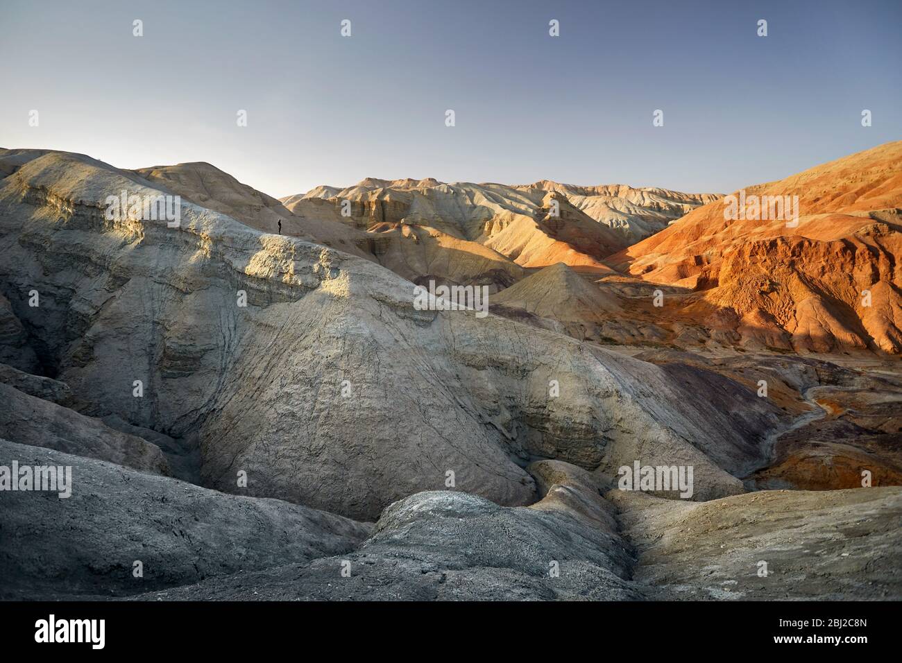 Petite personne dans les montagnes au coucher du soleil dans le parc du désert Altyn Emel au Kazakhstan Banque D'Images