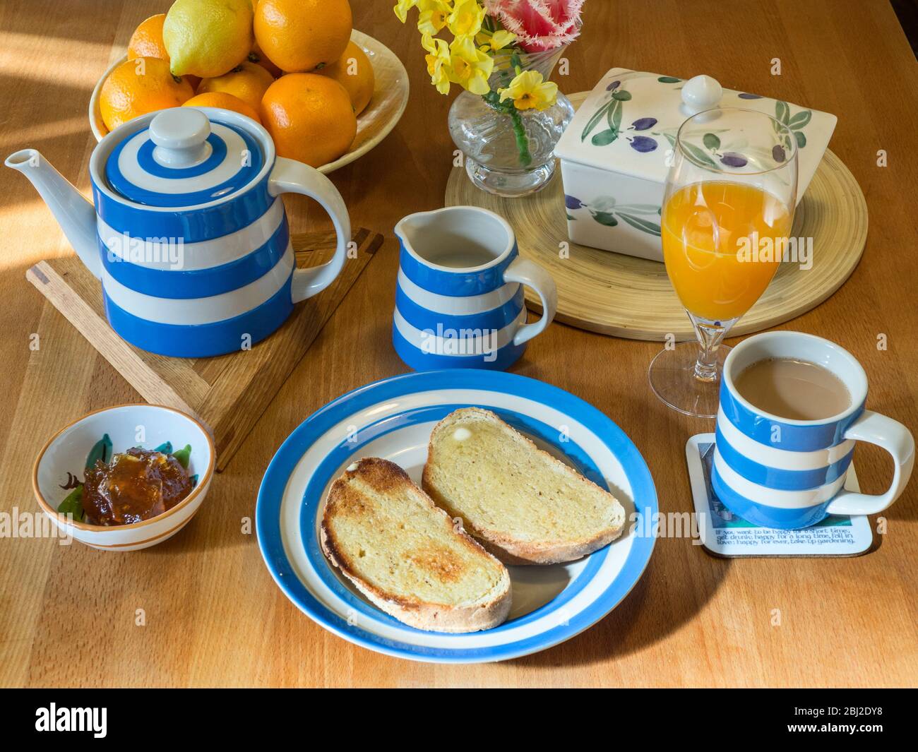 Table de cuisine en bois avec service de cornishware avec pain grillé et une tasse de thé Banque D'Images
