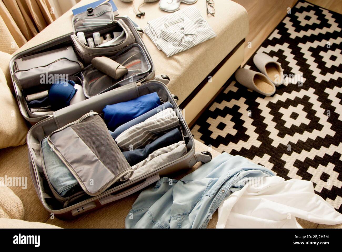 Valise grise ouverte avec différents vêtements emballés pour le voyage à la  maison. Style minimaliste nordique Photo Stock - Alamy