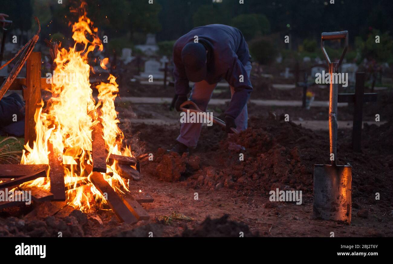 Les ouvriers du cimetière creusent pour enlever les restes humains et brûler des croix Banque D'Images