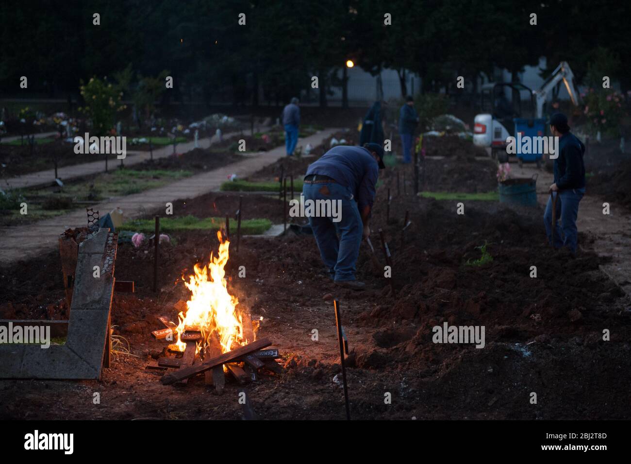 Les ouvriers du cimetière creusent pour enlever les restes humains et brûler des croix Banque D'Images