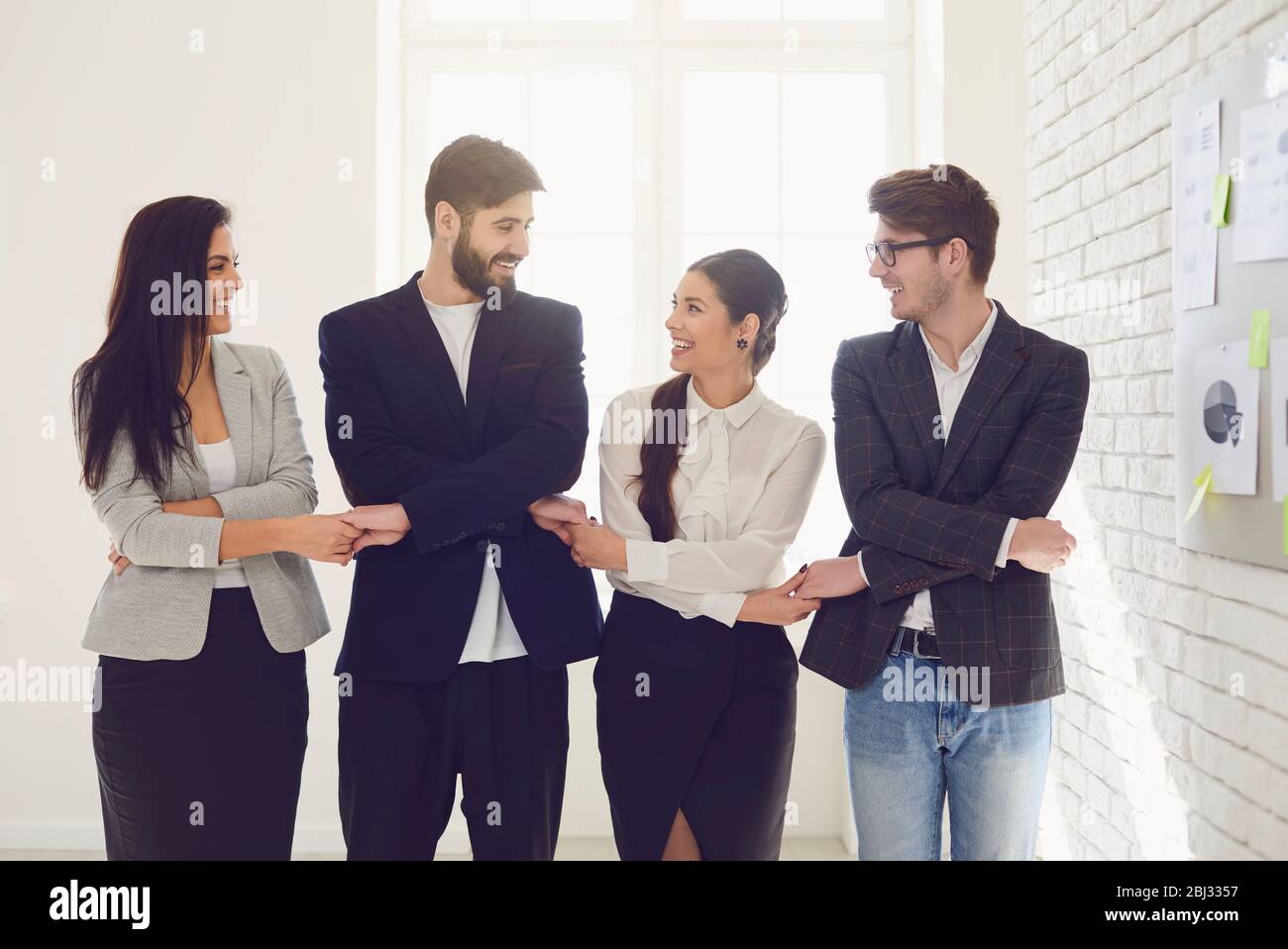 L'équipe créative des gens d'affaires tient les mains tout en se tenant à l'intérieur. Banque D'Images
