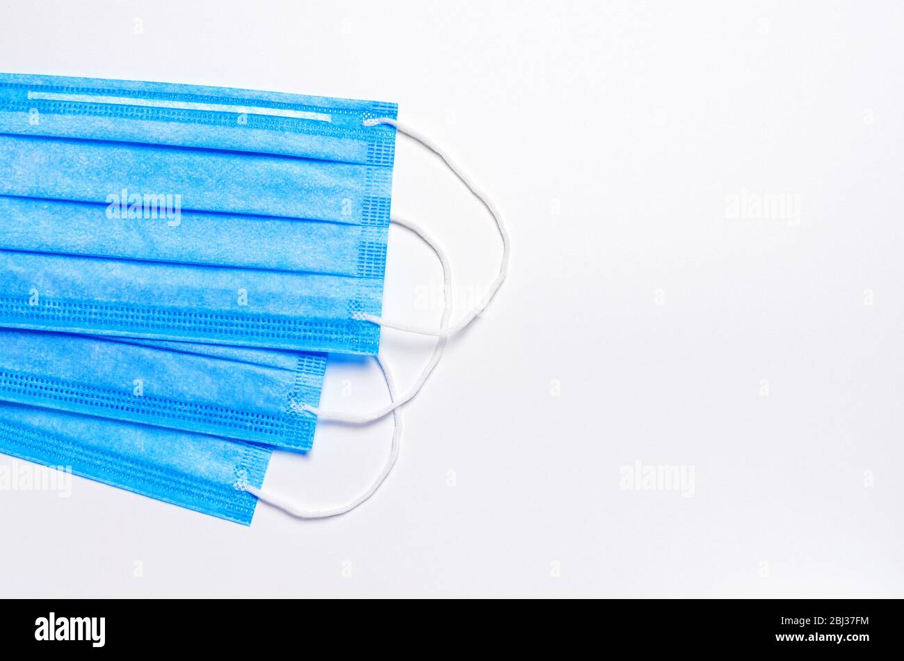 sur la gauche se trouvent trois masques faciaux bleus médicaux sur fond clair. antécédents médicaux. lamelle. espace de copie. contexte de nouvelles sur l'éclosion de coronavirus Banque D'Images