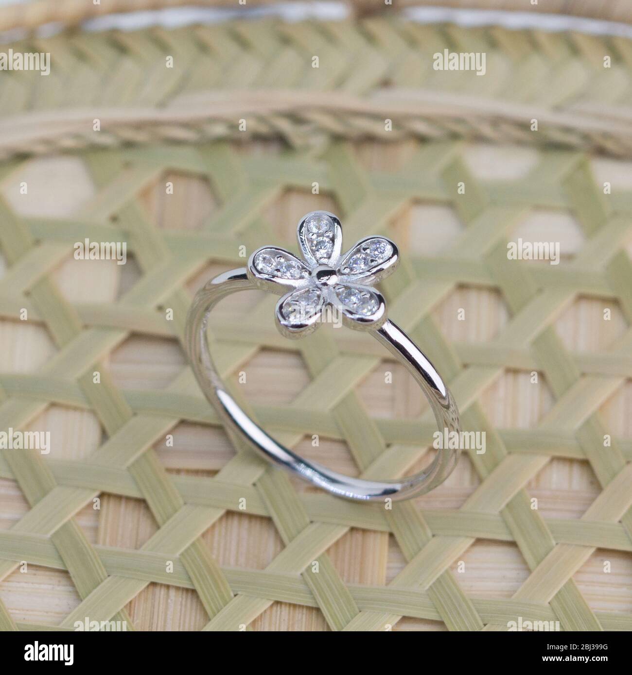 joli anneau argent en forme de fleur décoré d'un affichage en losange sur du bambou rasé Banque D'Images