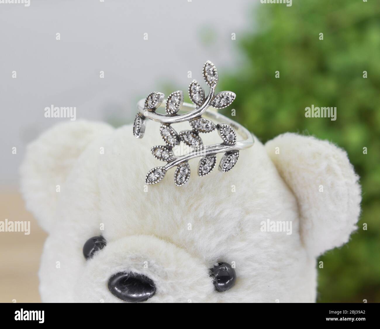 anneau argenté en forme de feuilles d'olive décorées de diamants s'affichent sur l'ours en peluche Banque D'Images