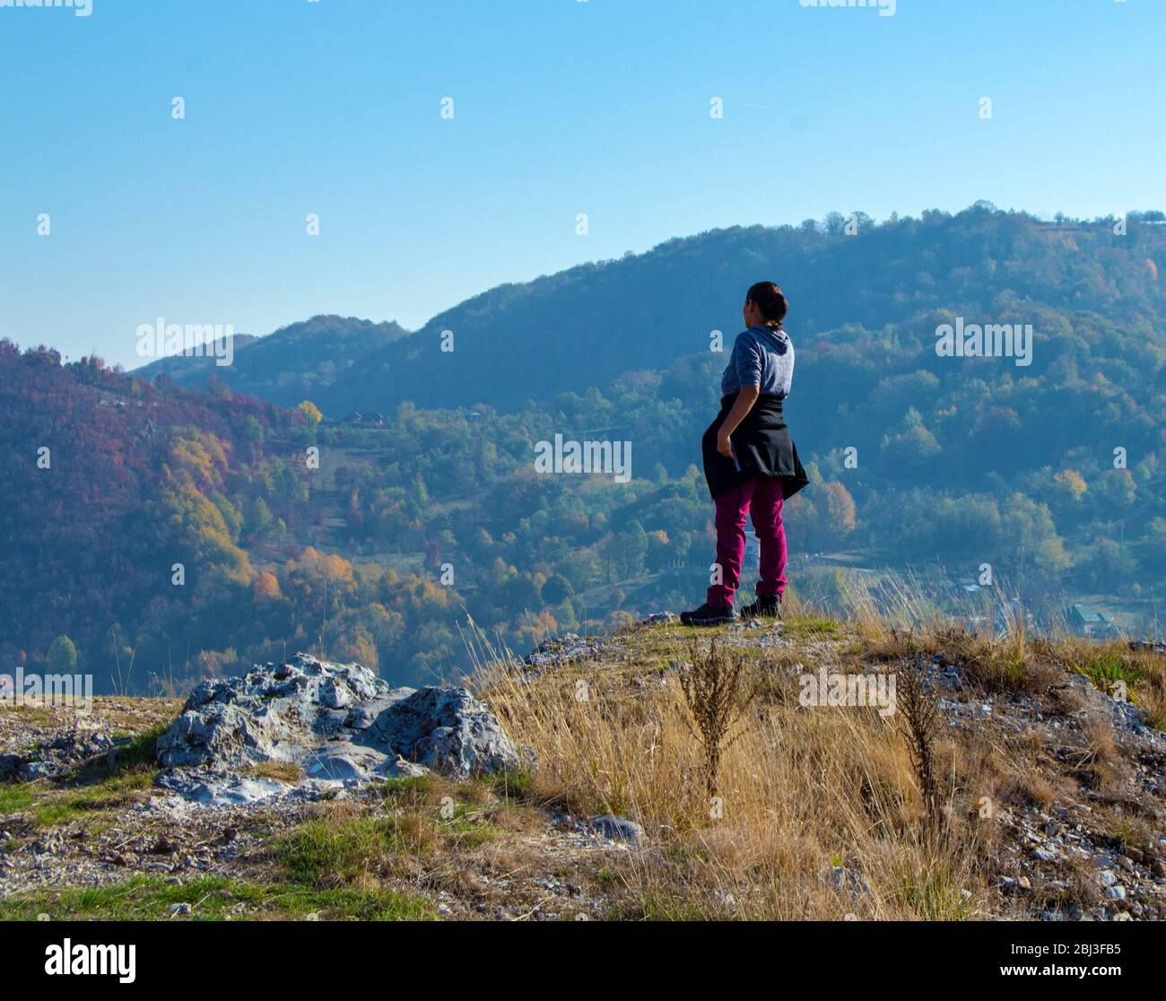 Femme debout au sommet d'une colline, en regardant la distance vers les montagnes, paysage serein tout en randonnée dans la campagne roumaine, randonnée Banque D'Images