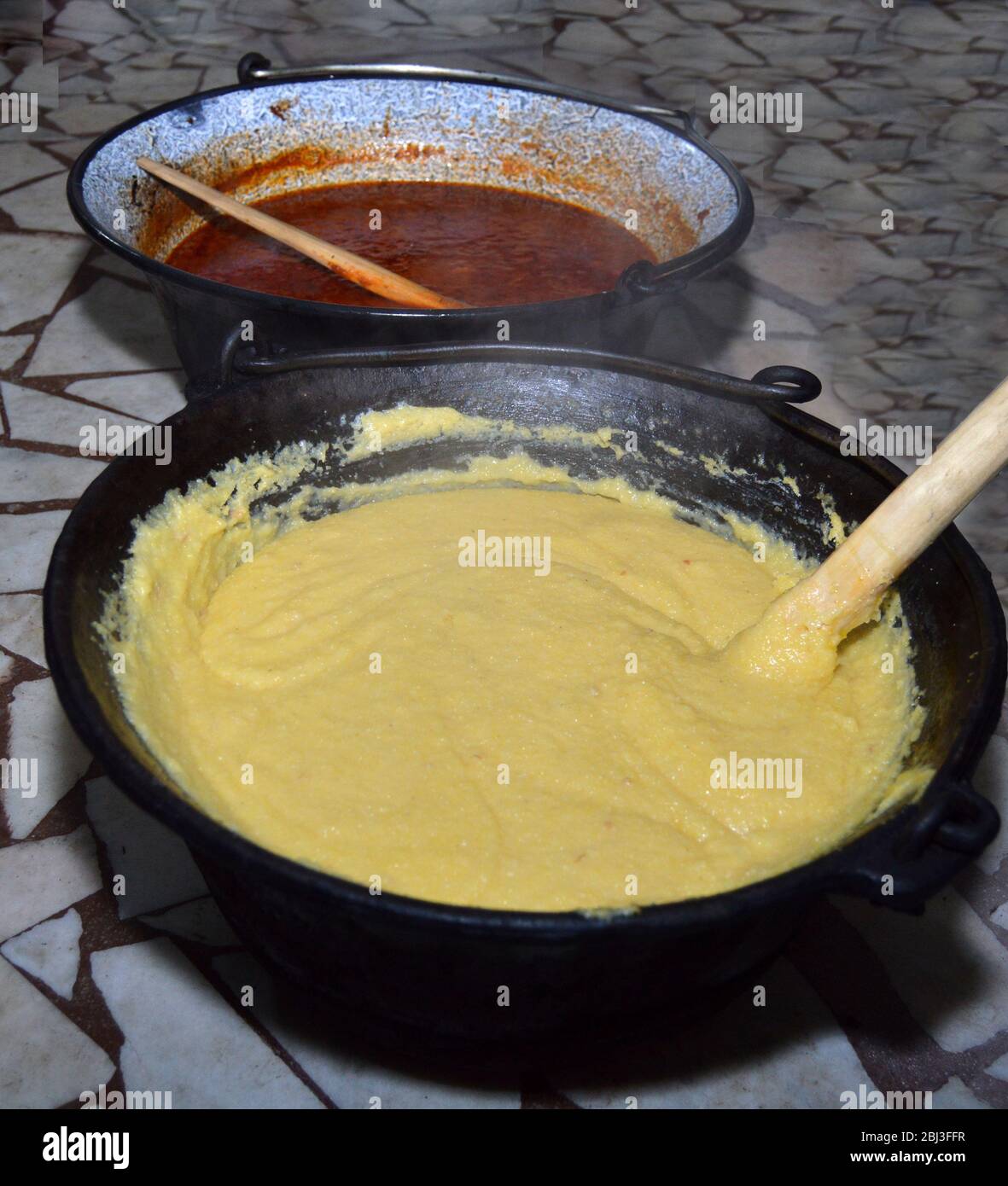 Gros plan de pots en fonte, l'un avec ragoût de viande et l'autre avec polenta traditionnelle roumaine plat 'maaliga', tout droit du feu et prêt à être servi Banque D'Images