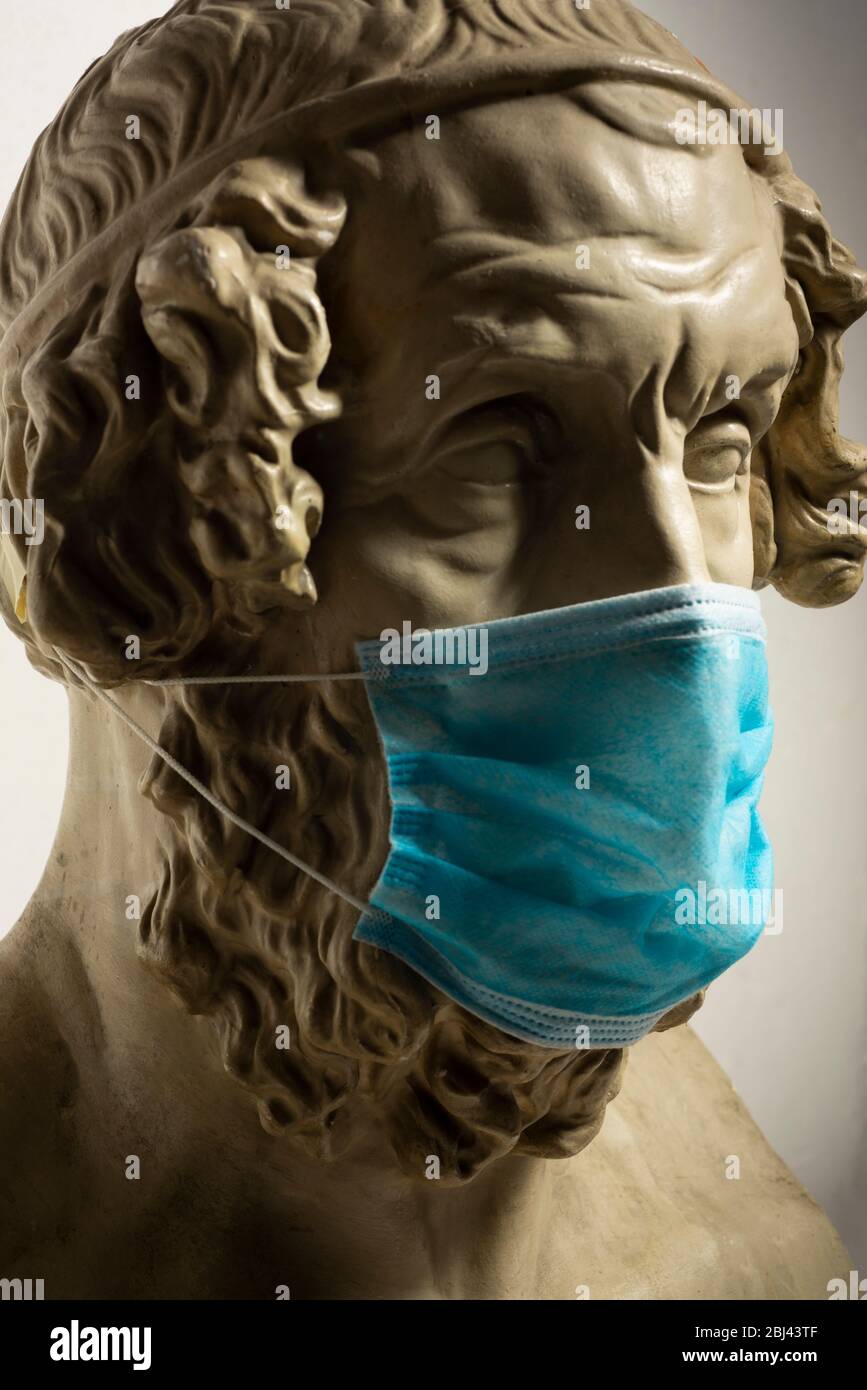 Copie en gypse de l'ancien Homer statue portant un masque de visage de virus Banque D'Images