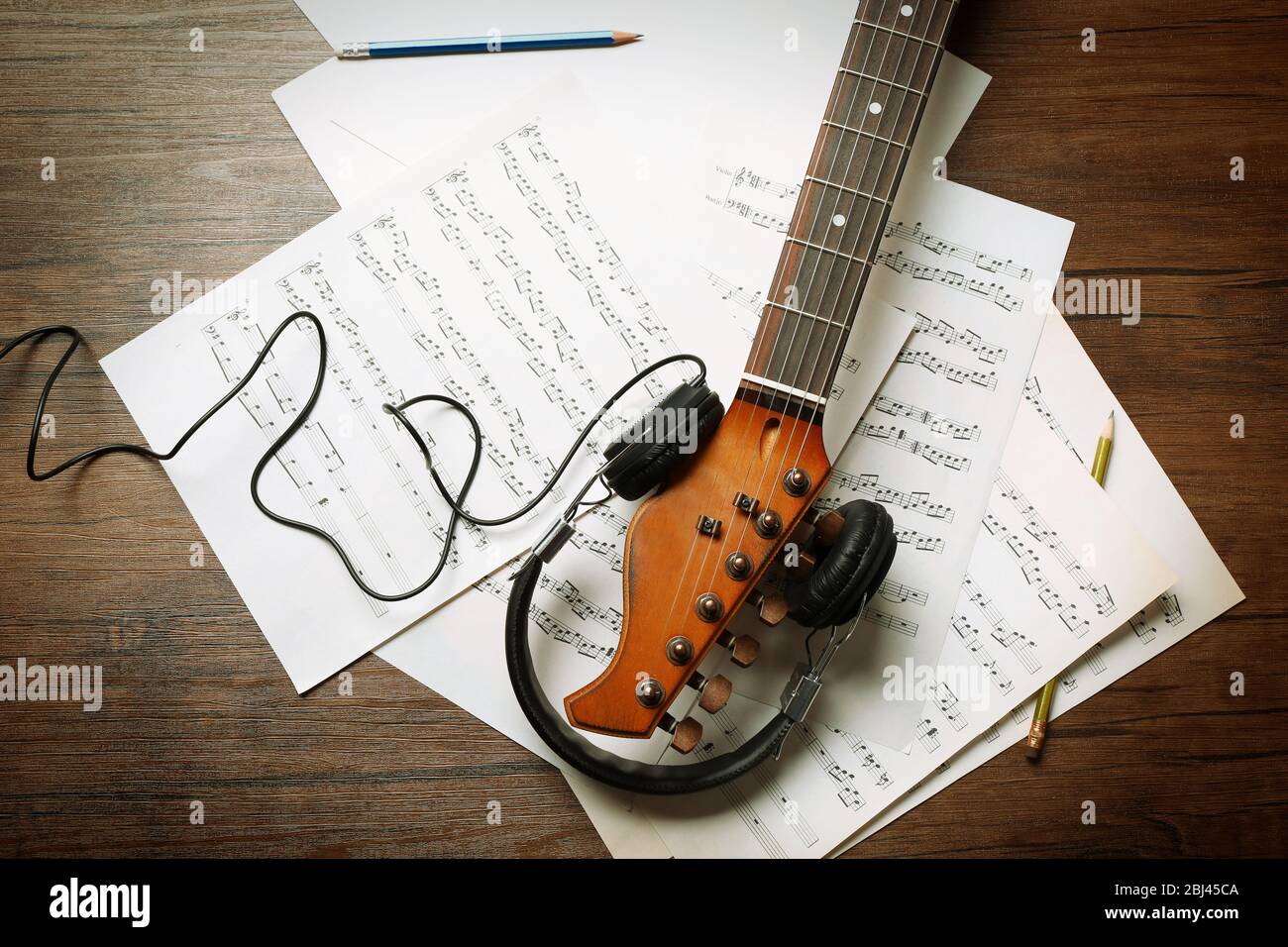 Guitare électrique et casque avec notes musicales sur fond en bois Banque D'Images