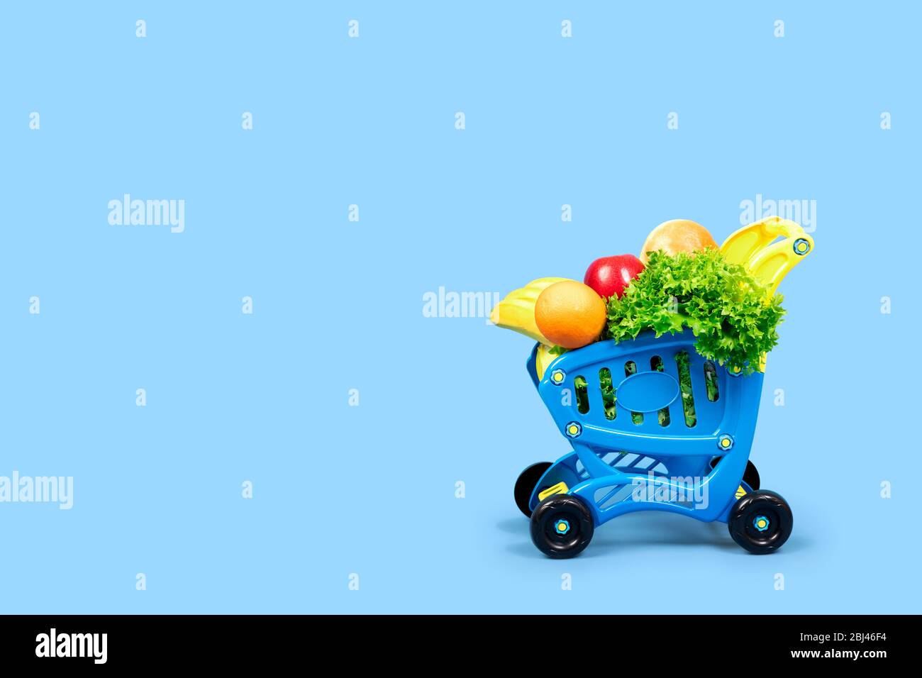 Une épicerie pleine de salade, d'oranges, de bananes, de pommes et de pain. Concept de gros plan avec place pour le texte sur un fond bleu. Pour les articles, ad Banque D'Images