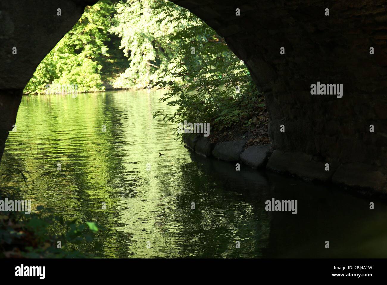 La rivière coule sous un pont de pierre Banque D'Images