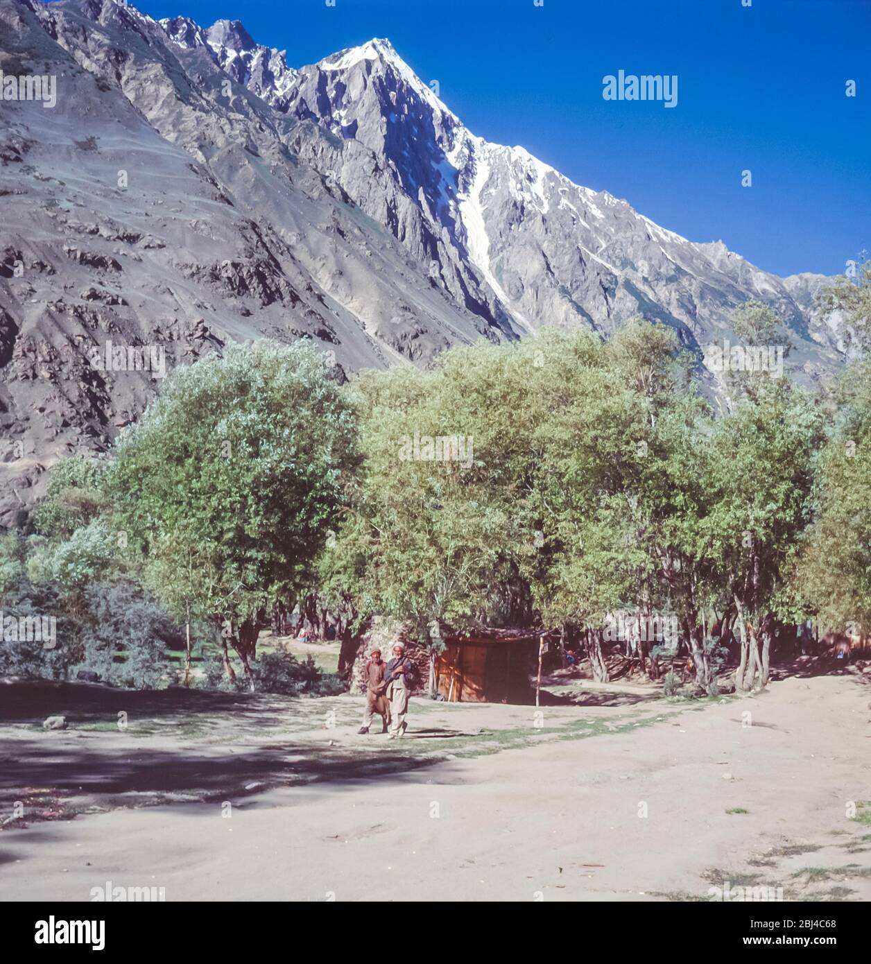 Pakistan, régions du nord des montagnes Karakoram. Les hommes de Balti se promènent dans les champs de blé et la verdure à la périphérie du village d'Askole, le dernier des villages avant les hautes montagnes des Glaciers de Baltoro et de Biafo Banque D'Images