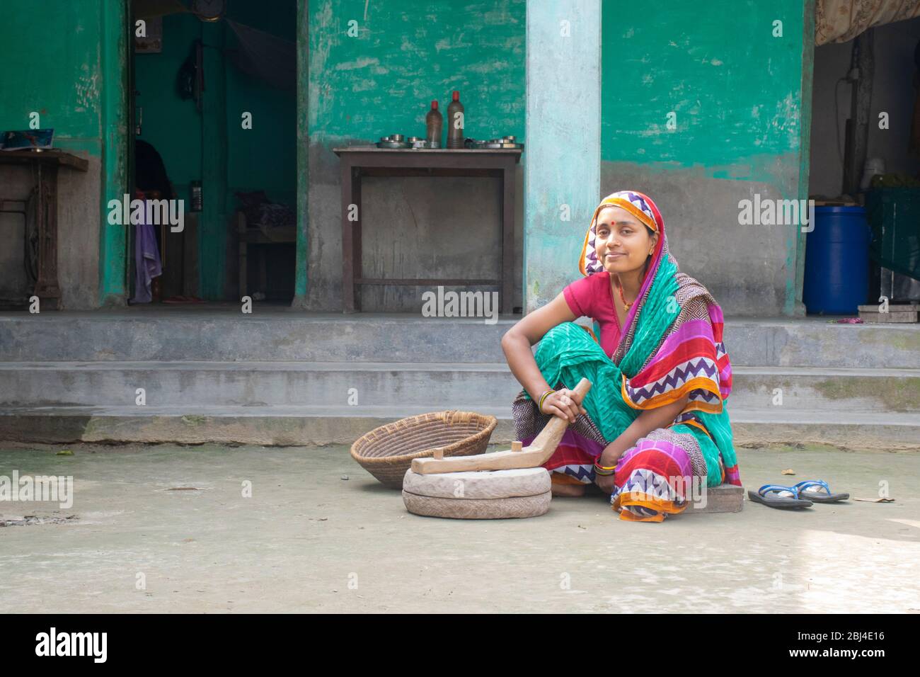 Femme indienne meulant la farine dans la pierre à poncer à sa maison dans un village Banque D'Images