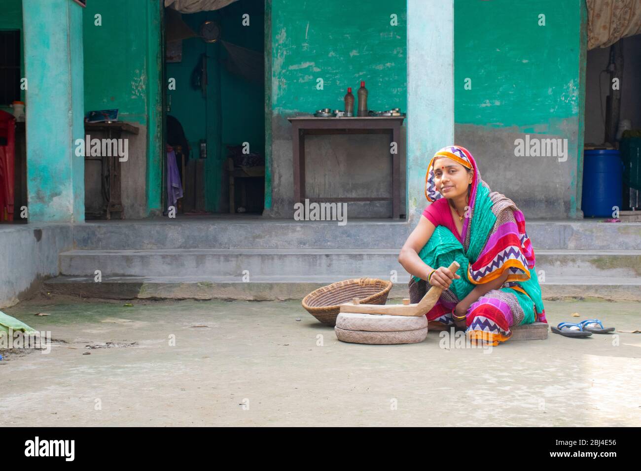 Femme indienne meulant la farine dans la pierre à poncer à sa maison dans un village Banque D'Images