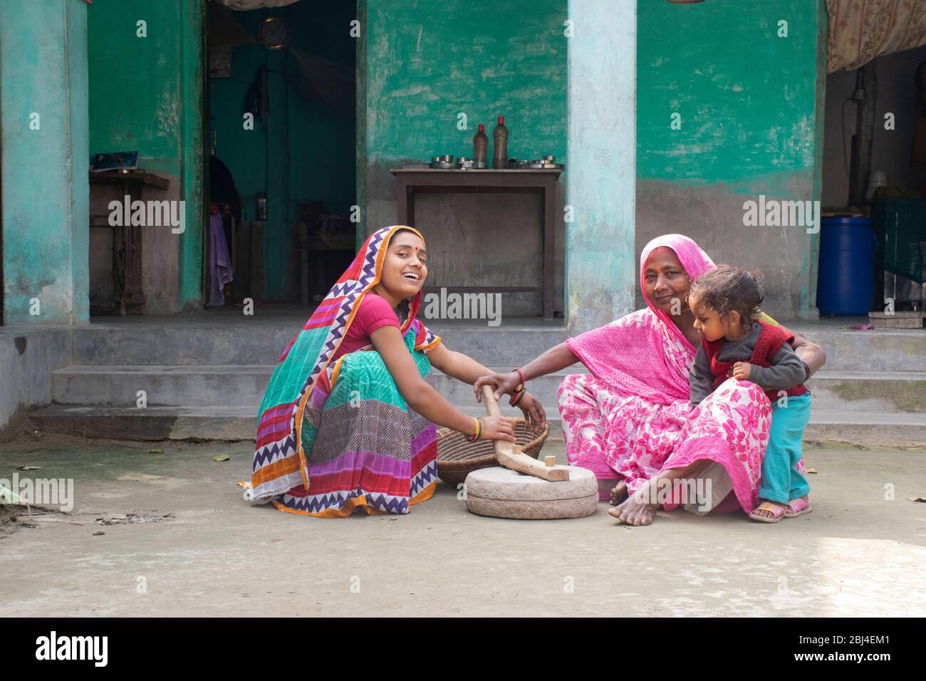 Femme indienne tenant un enfant et meuler de la farine dans un village Banque D'Images