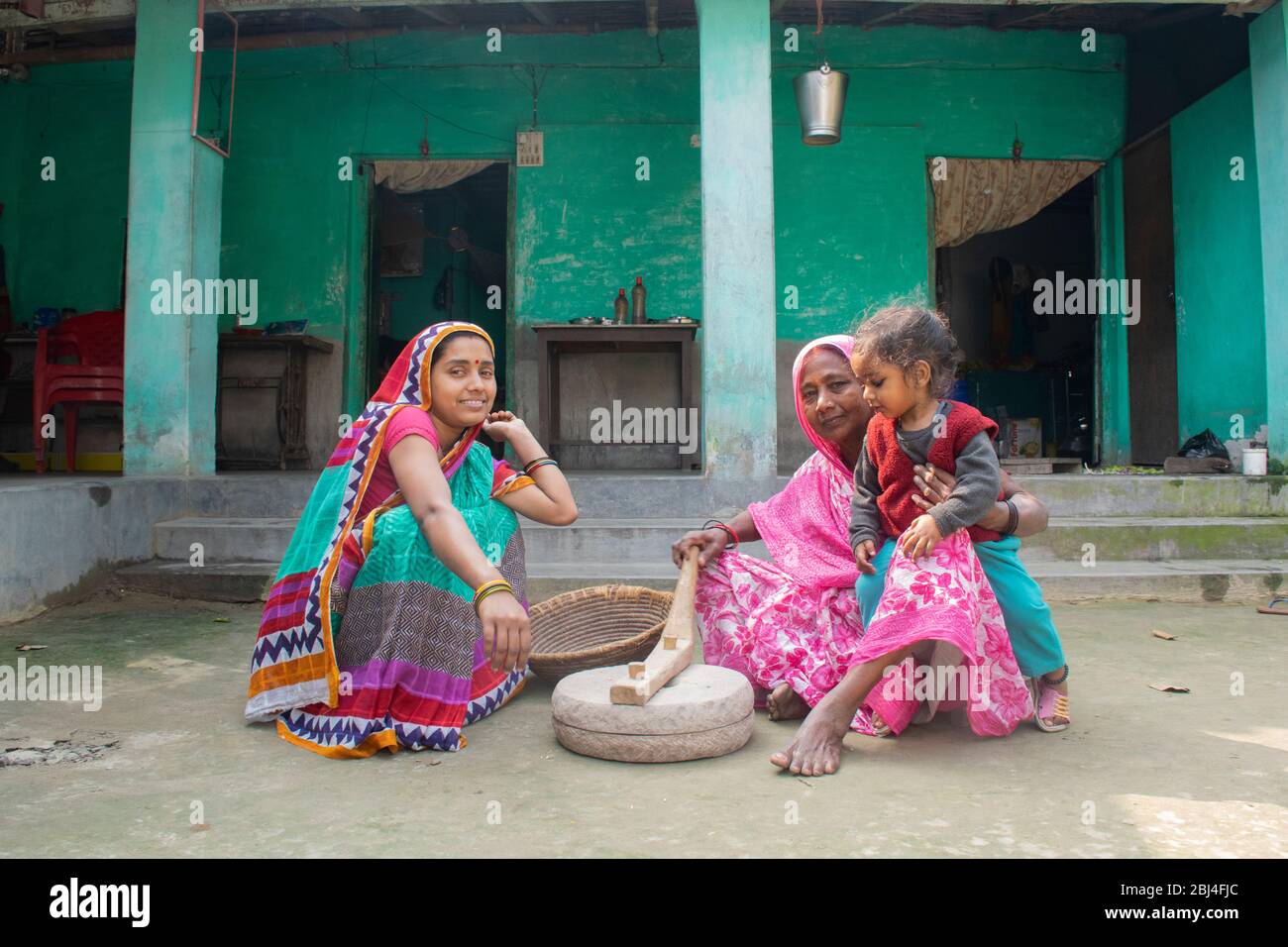 Femme indienne tenant un enfant et meuler de la farine dans un village Banque D'Images