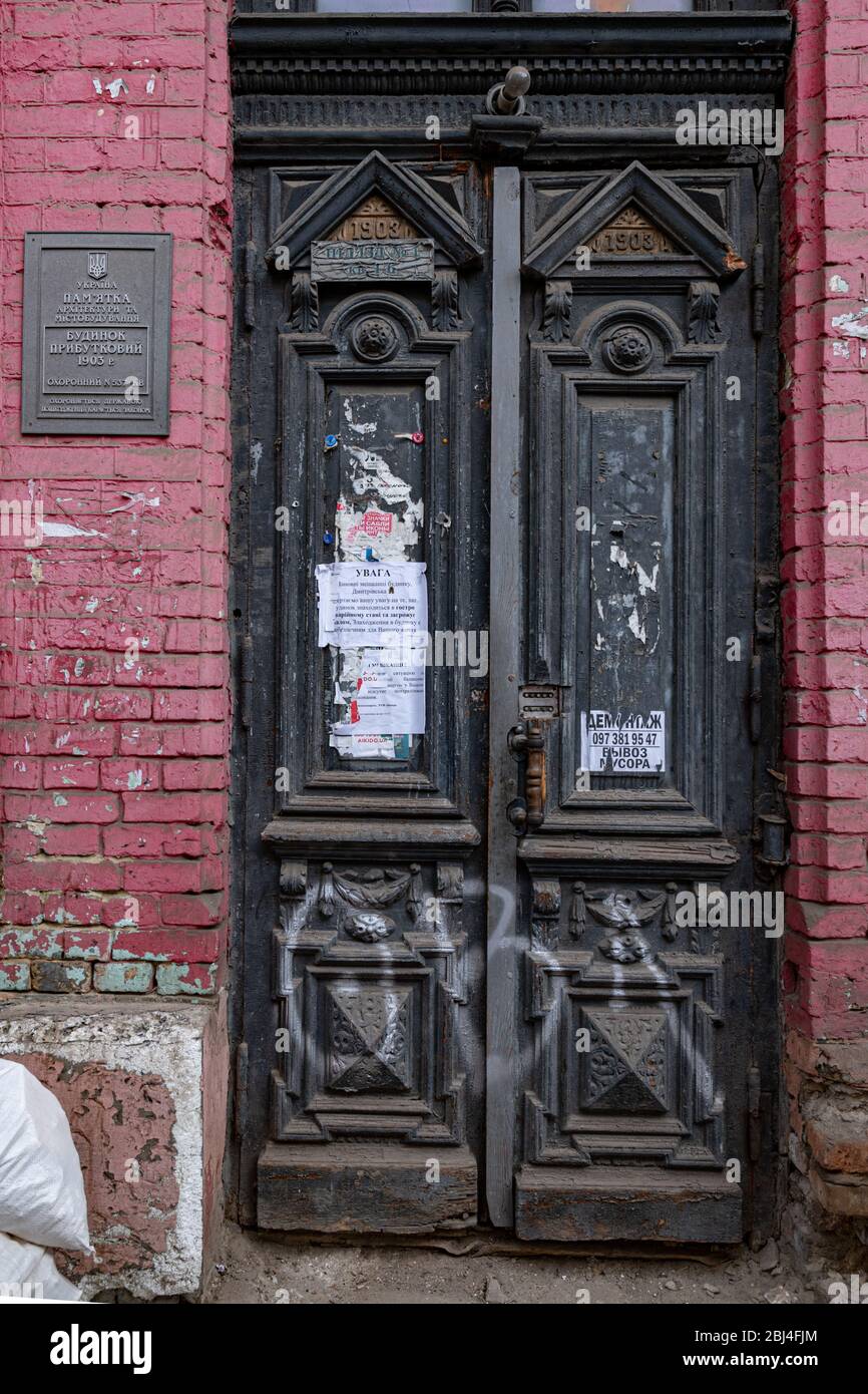 Entrée à l'ancien bâtiment historique abandonné avec une ancienne porte en bois de panneaux noirs ornés sur un mur de briques rouges. Architecture de la ville européenne. Bâtiment rétro e Banque D'Images