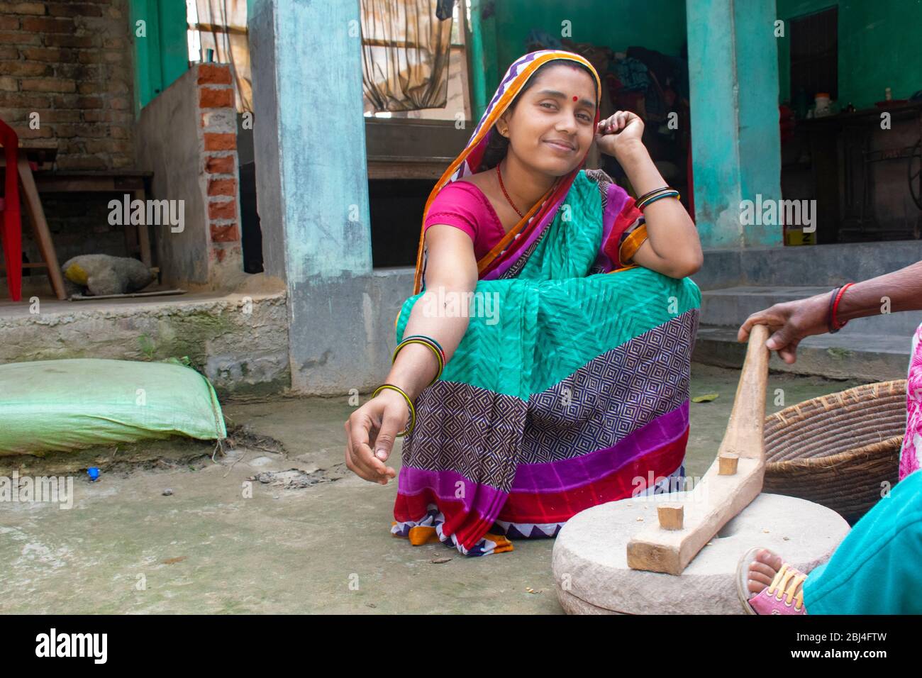 Femme indienne meulant la farine dans la pierre à poncer à sa maison dans un village Banque D'Images