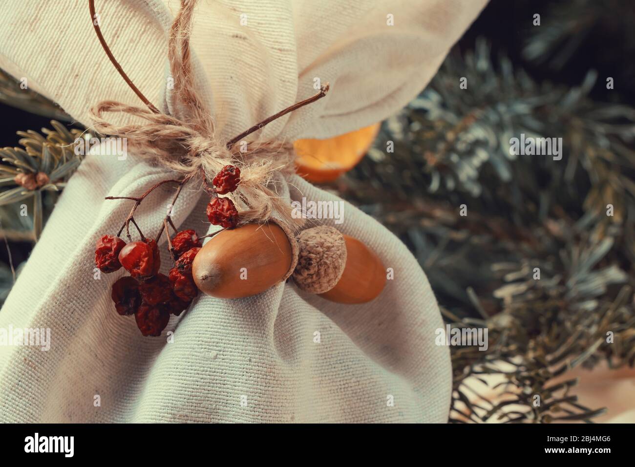 Concept de noël zéro déchet. Cadeau dans un sac décoré avec des matériaux naturels gros plan. Banque D'Images