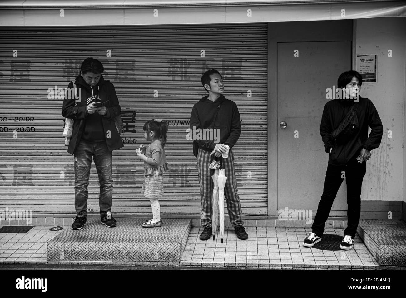 Trois hommes et une fille se tenant sur la rue Takeshita et se reposant pendant un moment pendant la visite au quartier de Harajuku Banque D'Images