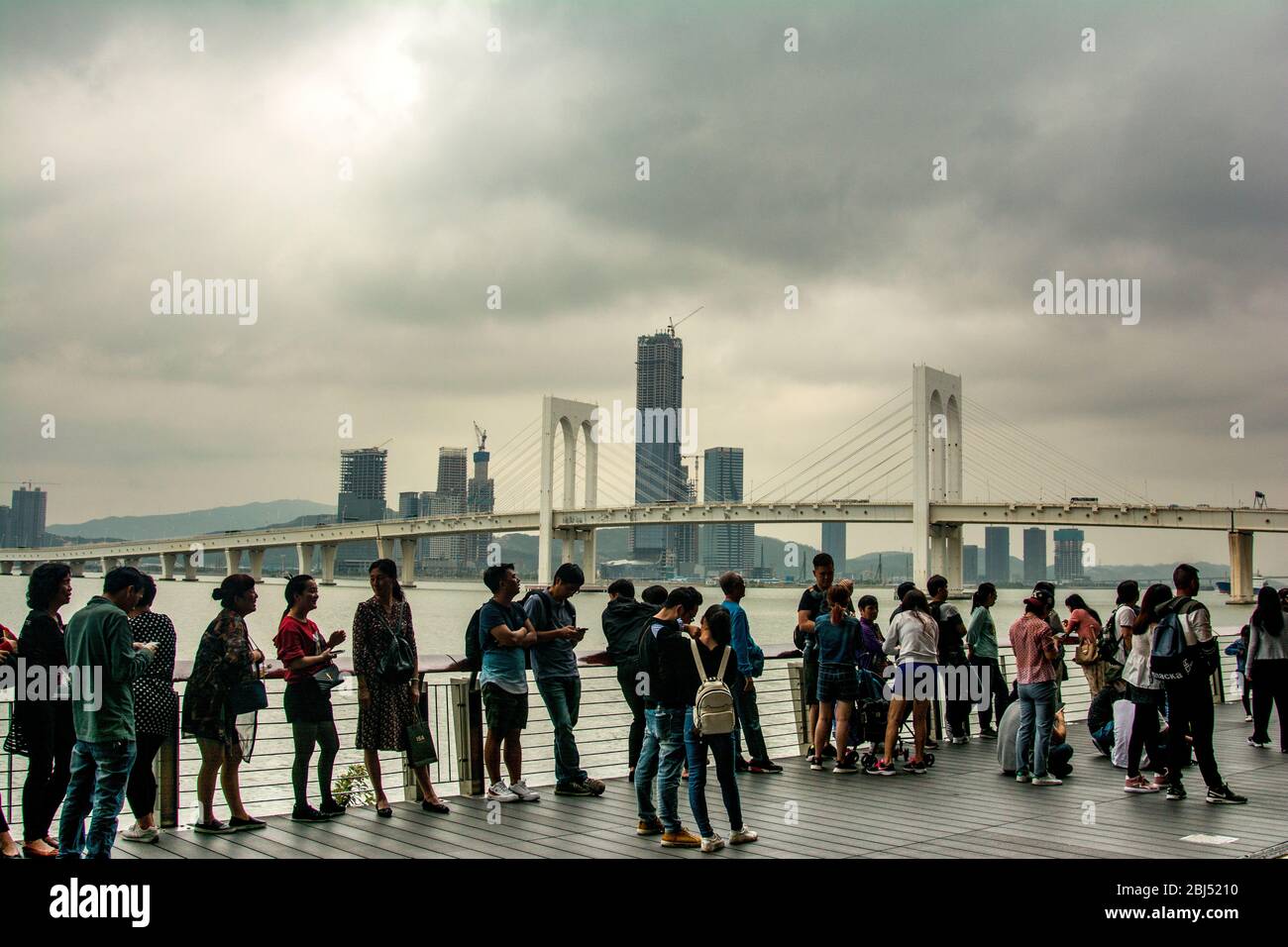 Les jeunes Chinois se tenant près de la rivière des perles lors d'une journée bien remplie à Macao. Banque D'Images