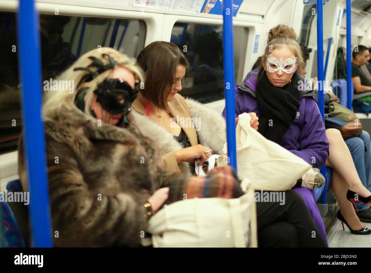 Trois femmes portent des masques de fête et des vestes d'hiver dans le métro londonien, en Angleterre Banque D'Images