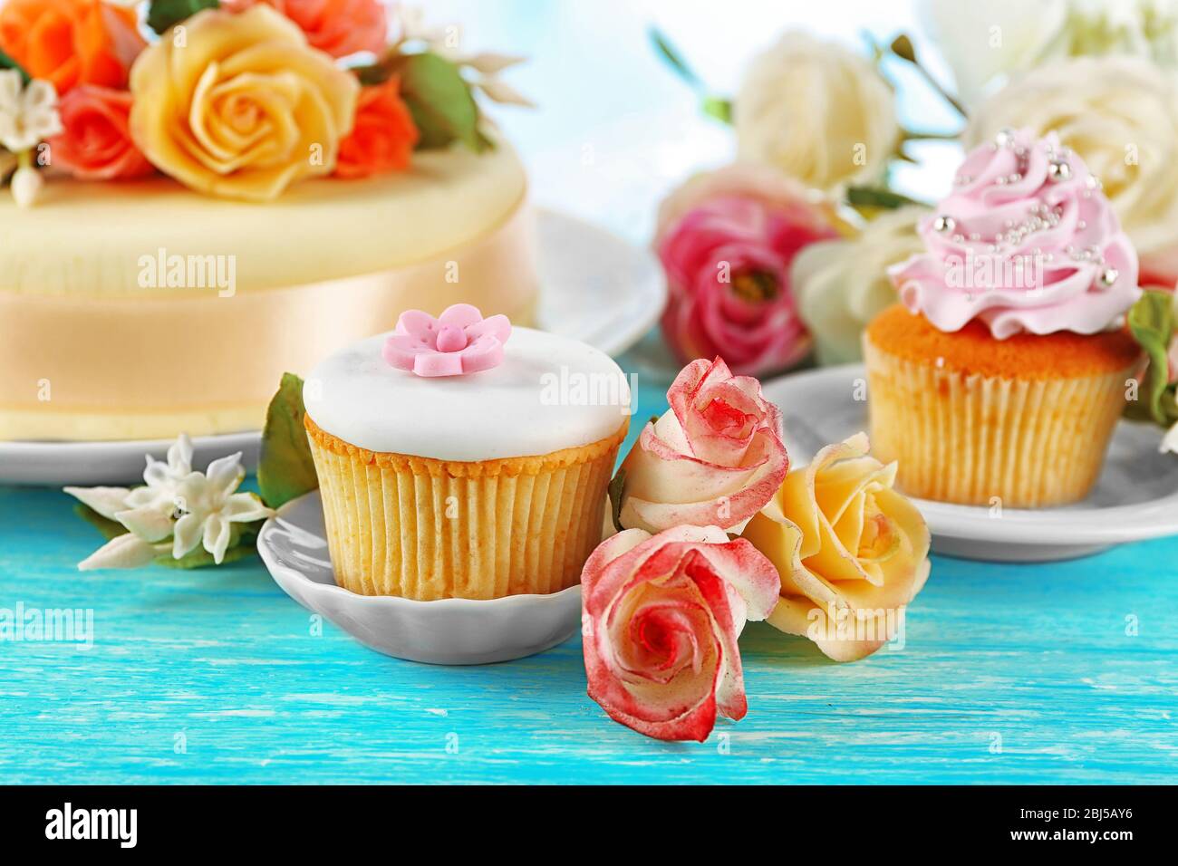 Gateau Avec Des Fleurs De Pate De Sucre Et Des Cupcakes Sur Fond Clair Photo Stock Alamy