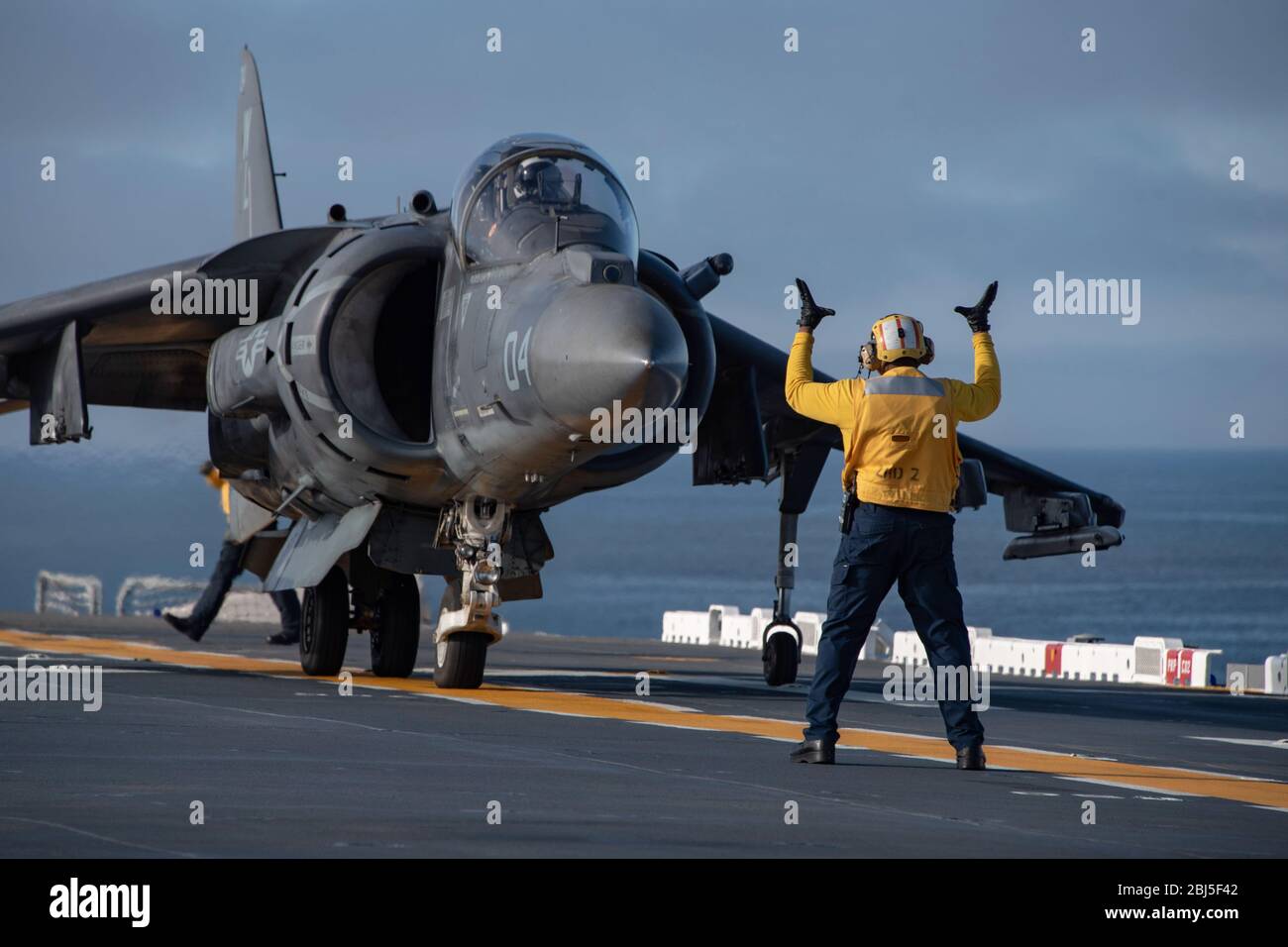 La marine américaine ABM First Class Lanton Jamison, signale un avion de chasse AV/8 B Harrier attaché aux Tomcats du Escadron d'attaque marine 311 sur le pont de vol du navire d'assaut amphibie de la classe Wasp USS Essex pendant les opérations de vol le 25 avril 2020 dans le Pacifique oriental. Banque D'Images