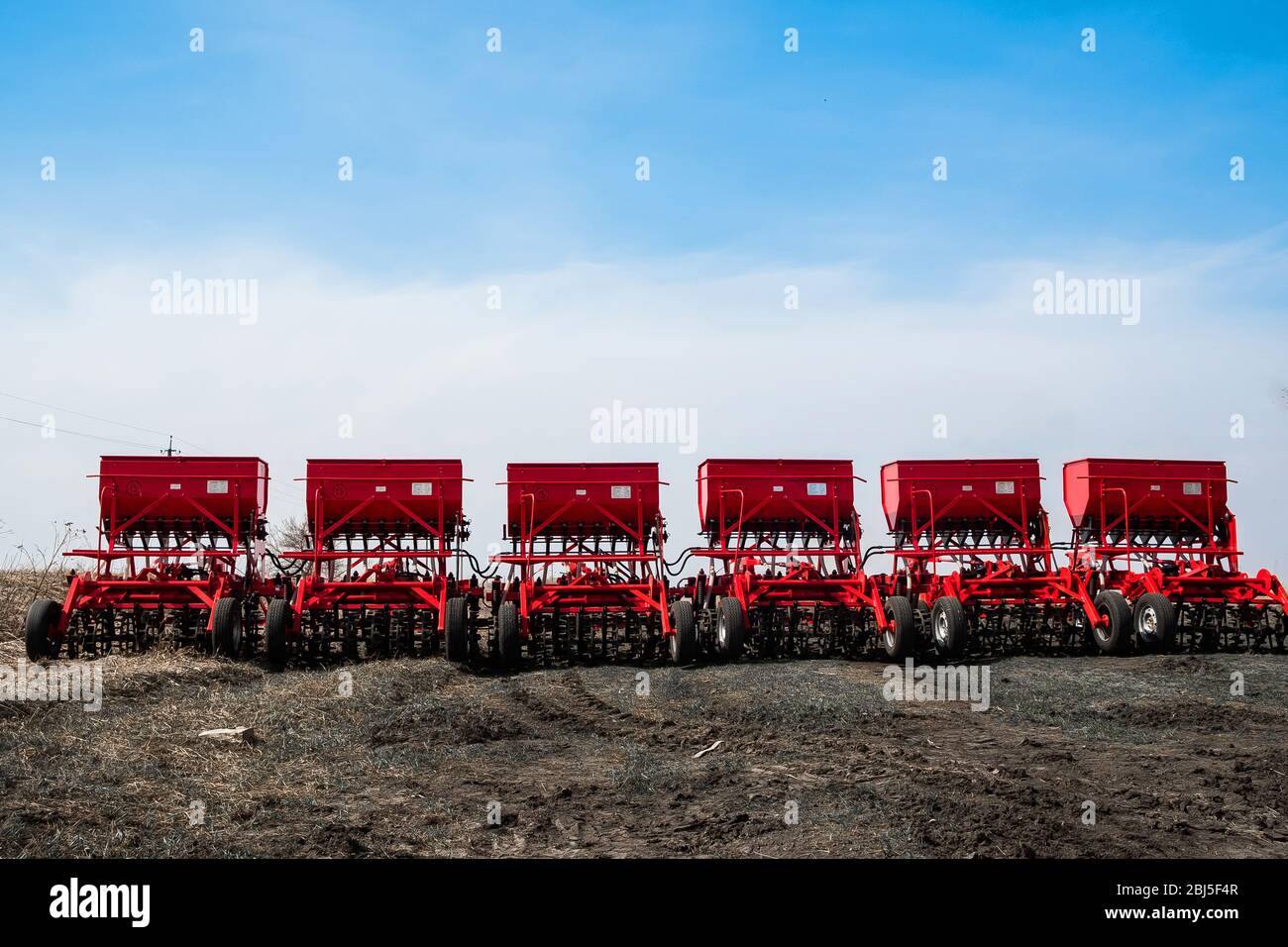 Moissonneuse-batteuse et charrue rouges, pulvérisateur traîné avec réservoir et liquide. Machines pour l'agriculture et l'agriculture. Dispositifs d'élevage de charrue Banque D'Images