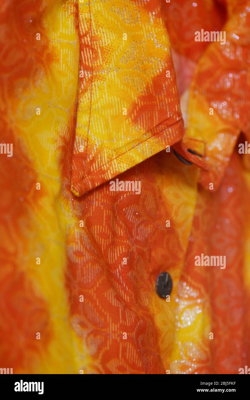 Image verticale d'une chemise à boutons de Fidji, à l'été, avec collage tropical orange, jaune et argent. Banque D'Images