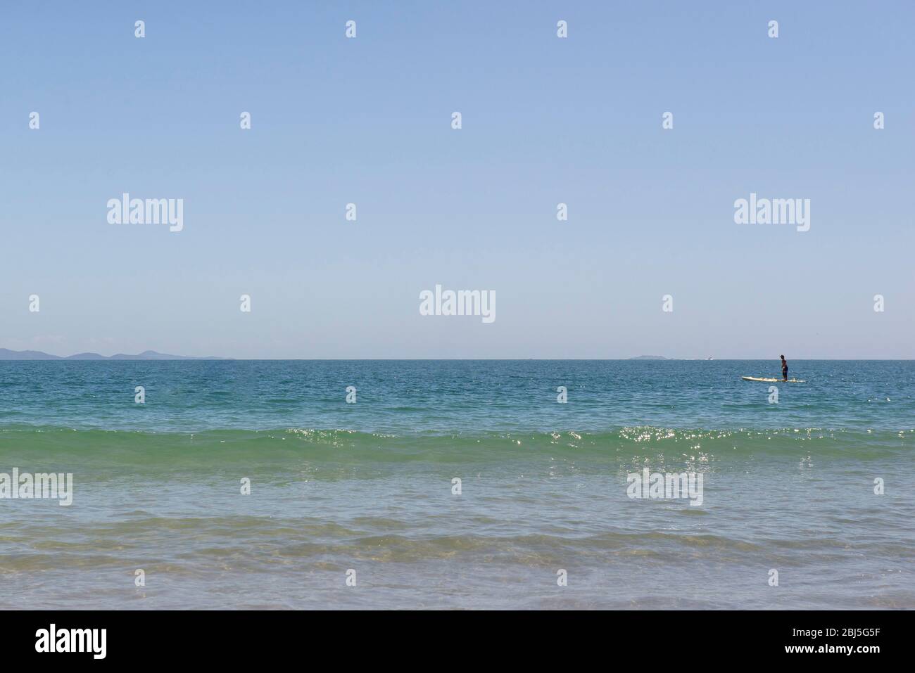 Belle plage dans le sud du Brésil - Ville de Florianopolis. Vue magnifique sur la mer verdâtre. Journée ensoleillée sans nuages - ciel clair en été. Homme sur stan Banque D'Images