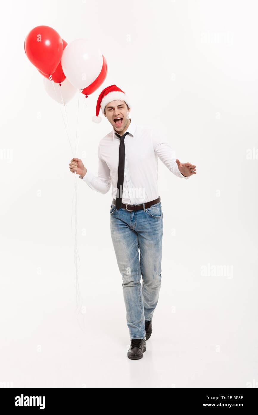 Concept de Noël - beau homme d'affaires heureux de marcher avec ballon rouge célébrer le joyeux noël et heureux nouvel an porter chapeau de santa. Banque D'Images