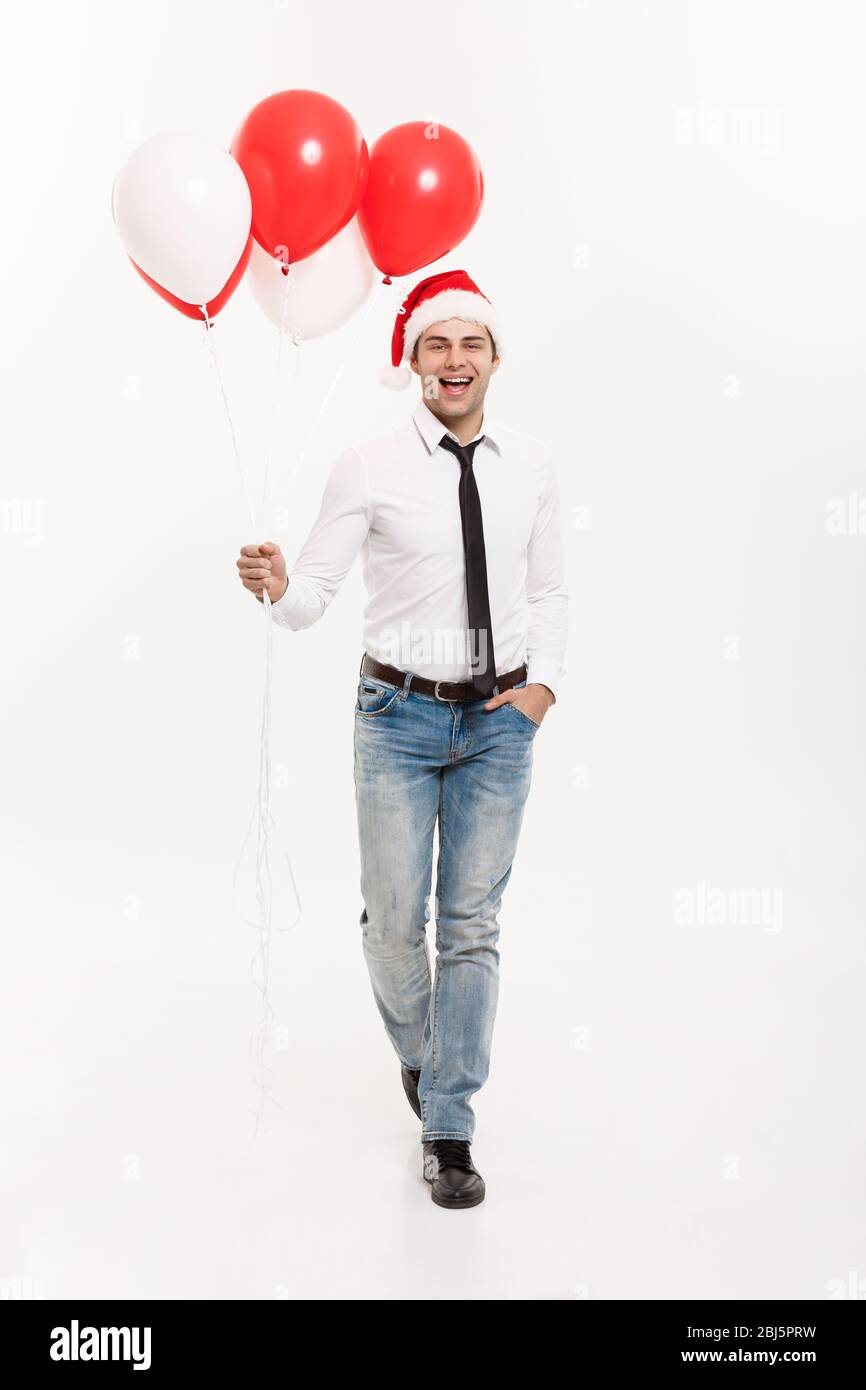 Concept de Noël - beau homme d'affaires heureux de marcher avec ballon rouge célébrer le joyeux noël et heureux nouvel an porter chapeau de santa. Banque D'Images