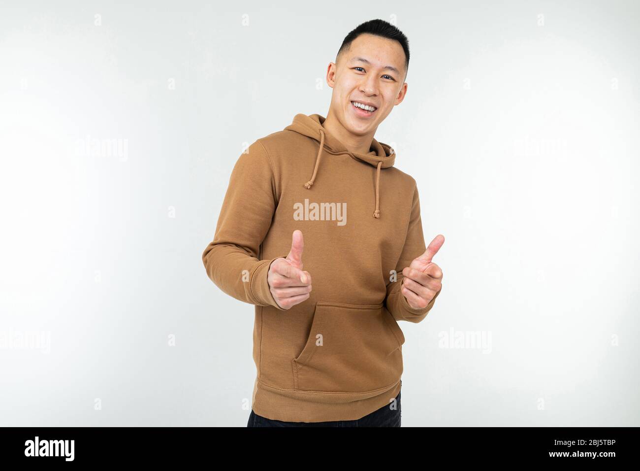 un homme asiatique confiant dans un sweat à capuche marron montre des mains comme sur fond blanc. Banque D'Images
