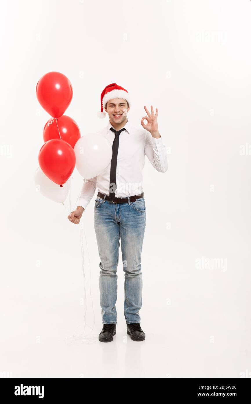 Concept de Noël - beau homme d'affaires heureux de marcher avec ballon rouge célébrer le joyeux noël et heureux nouvel an porter chapeau de santa. Banque D'Images