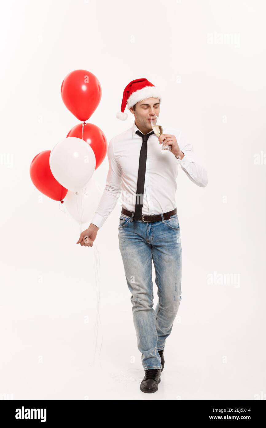 Concept de Noël - beau homme d'affaires heureux de marcher avec ballon rouge célébrer le joyeux noël et heureux nouvel an porter chapeau de santa. Banque D'Images