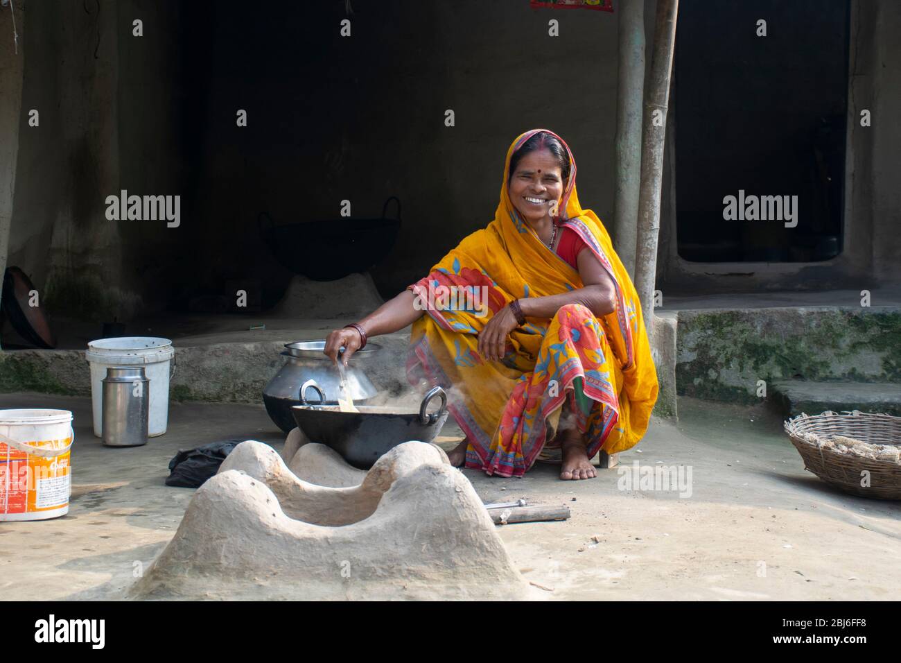 Rural Indian Woman cuisine de nourriture dans la cuisine à l'aide de poêle à bois Banque D'Images