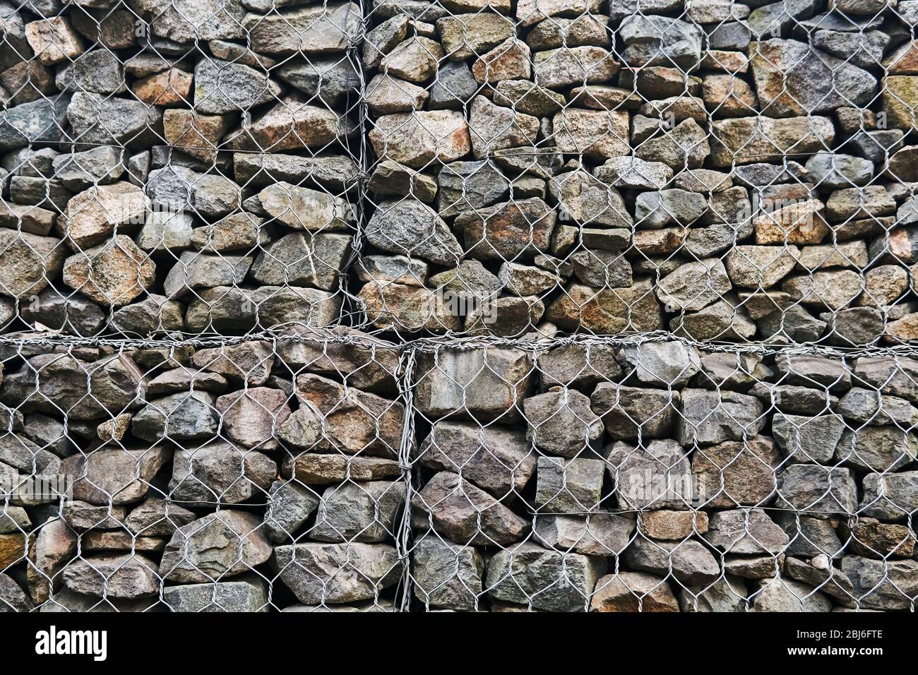 contexte - mur de gabion de filet de fil hexagonal avec des rochers de granit Banque D'Images