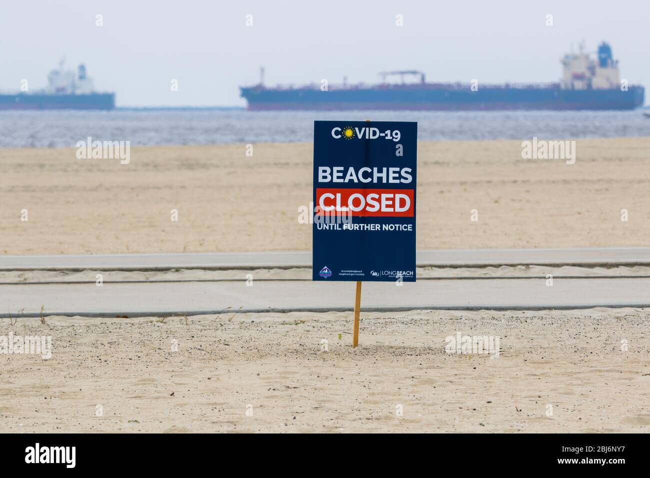 Plage fermée Covid19 panneaux avec des pétroliers ancrés au large de la côte de long Beach, Californie du Sud; États-Unis. Banque D'Images