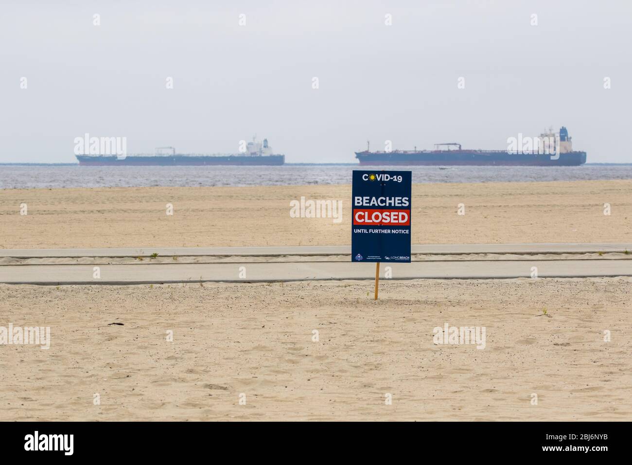 Plage fermée Covid19 panneaux avec des pétroliers ancrés au large de la côte de long Beach, Californie du Sud; États-Unis. Banque D'Images