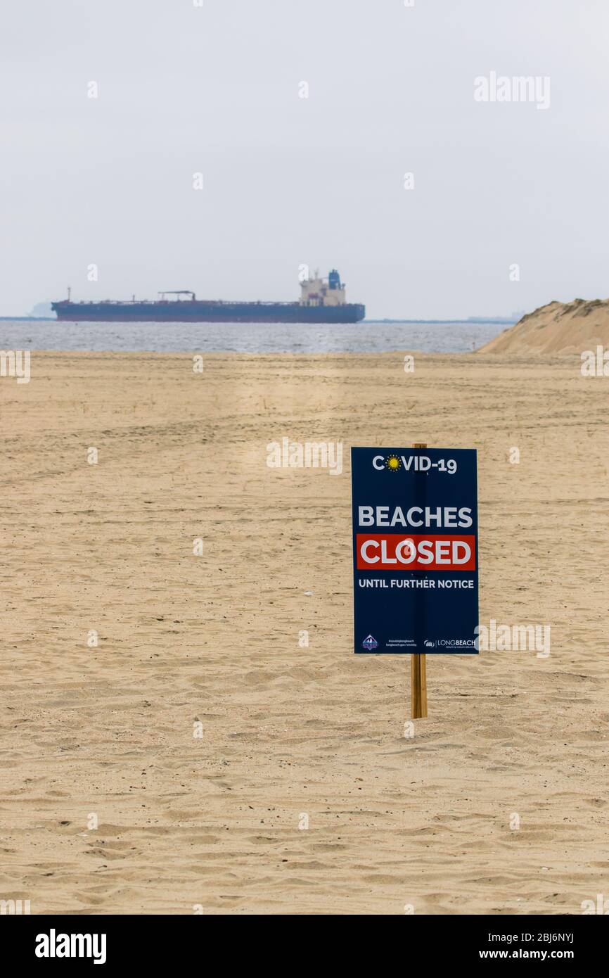 Plage fermée Covid19 panneaux avec des pétroliers ancrés au large de la côte de long Beach, Californie du Sud; États-Unis. Banque D'Images